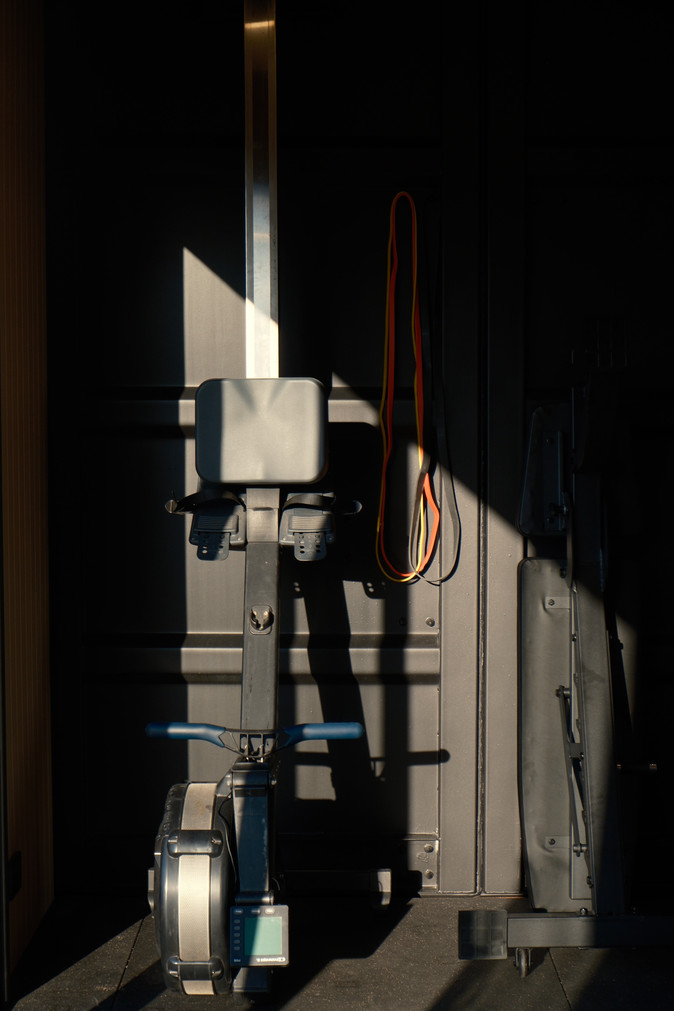 Rower and bands against the container wall in hard afternoon light